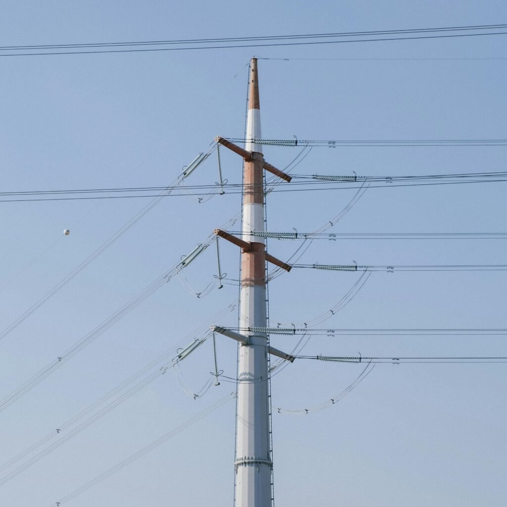 pexels-photo-7663320-7663320 A towering high voltage power line structure set against a clear blue sky, representing energy infrastructure.